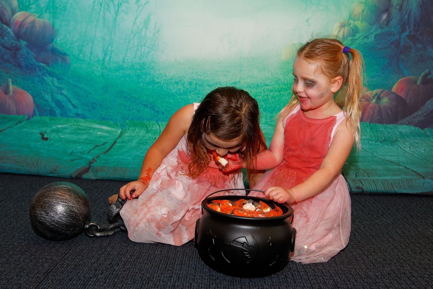 Halloween themed photo with black cauldron prop against spooky forest backdrop.