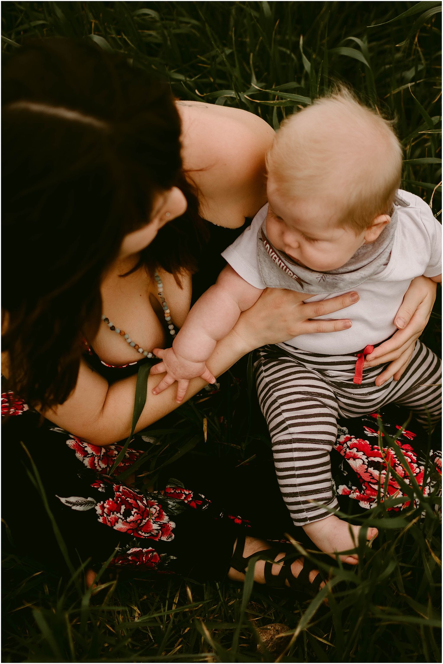 Intimate portrait in tall grass featuring floral dress and striped pants.