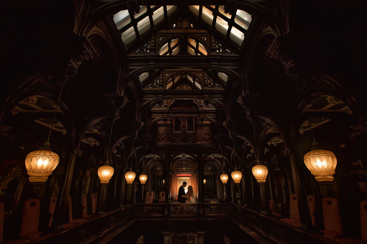 Atmospheric corridor with wooden beams and glowing lanterns creates romantic wedding ambiance.