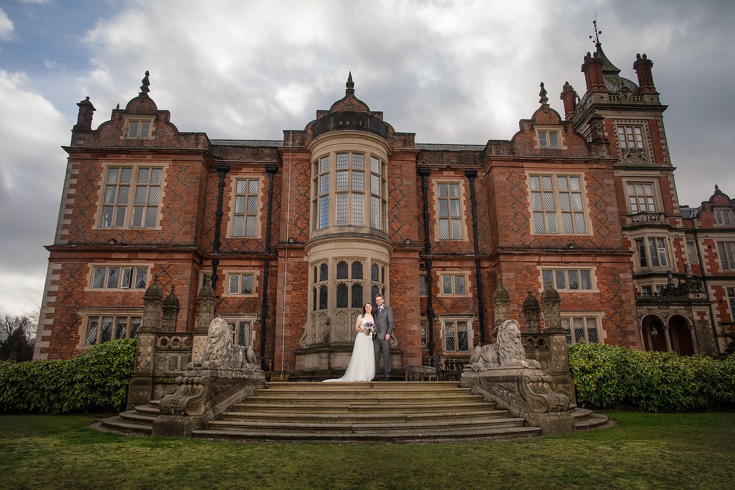 Elegant red brick Victorian mansion with ornate architectural details serves as wedding venue.