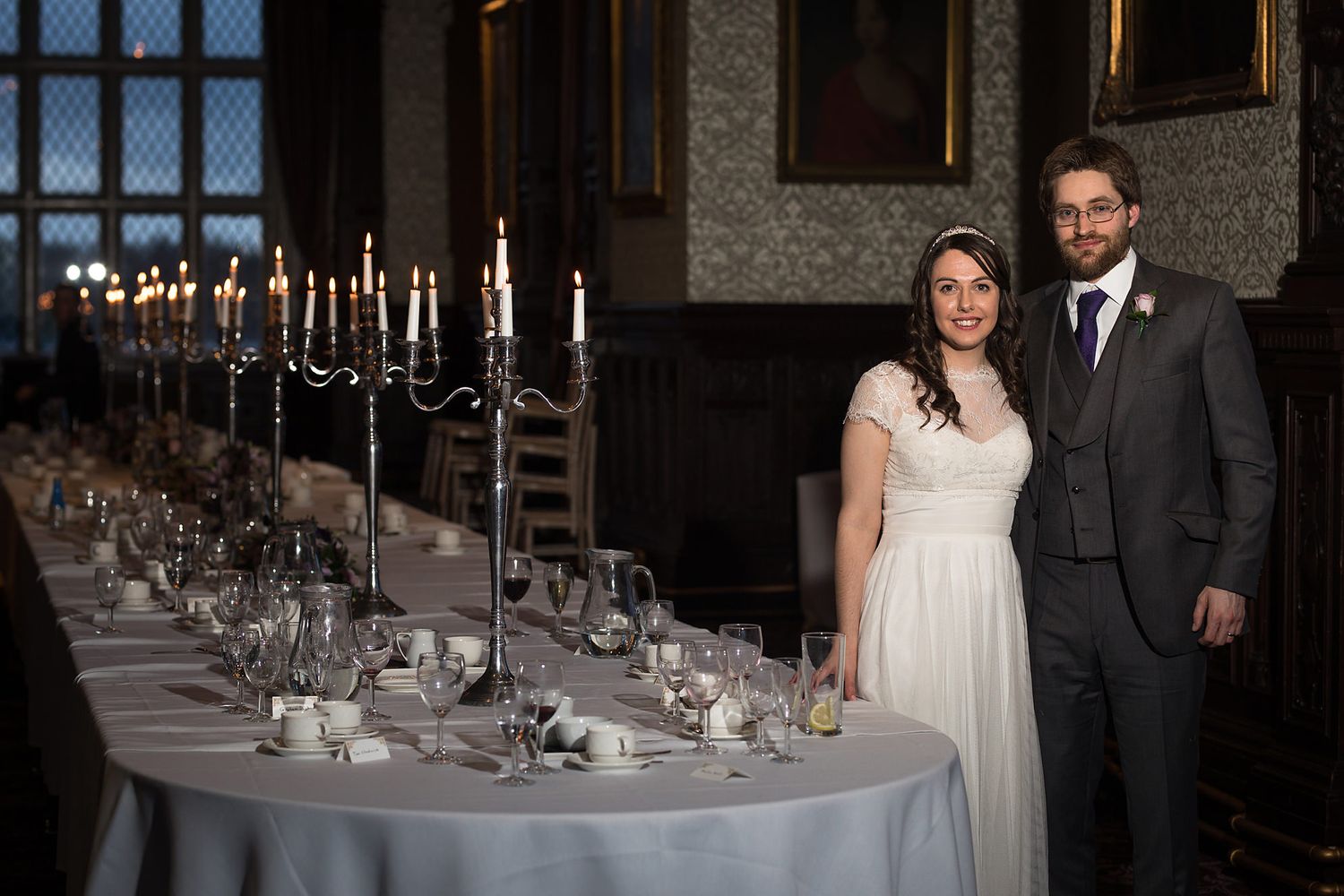 Formal dining setup with candelabras and couple standing by elegant table setting.