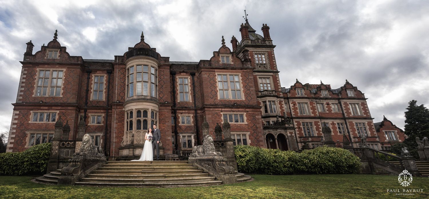 Grand Victorian red brick mansion wedding venue with dramatic cloudy sky.
