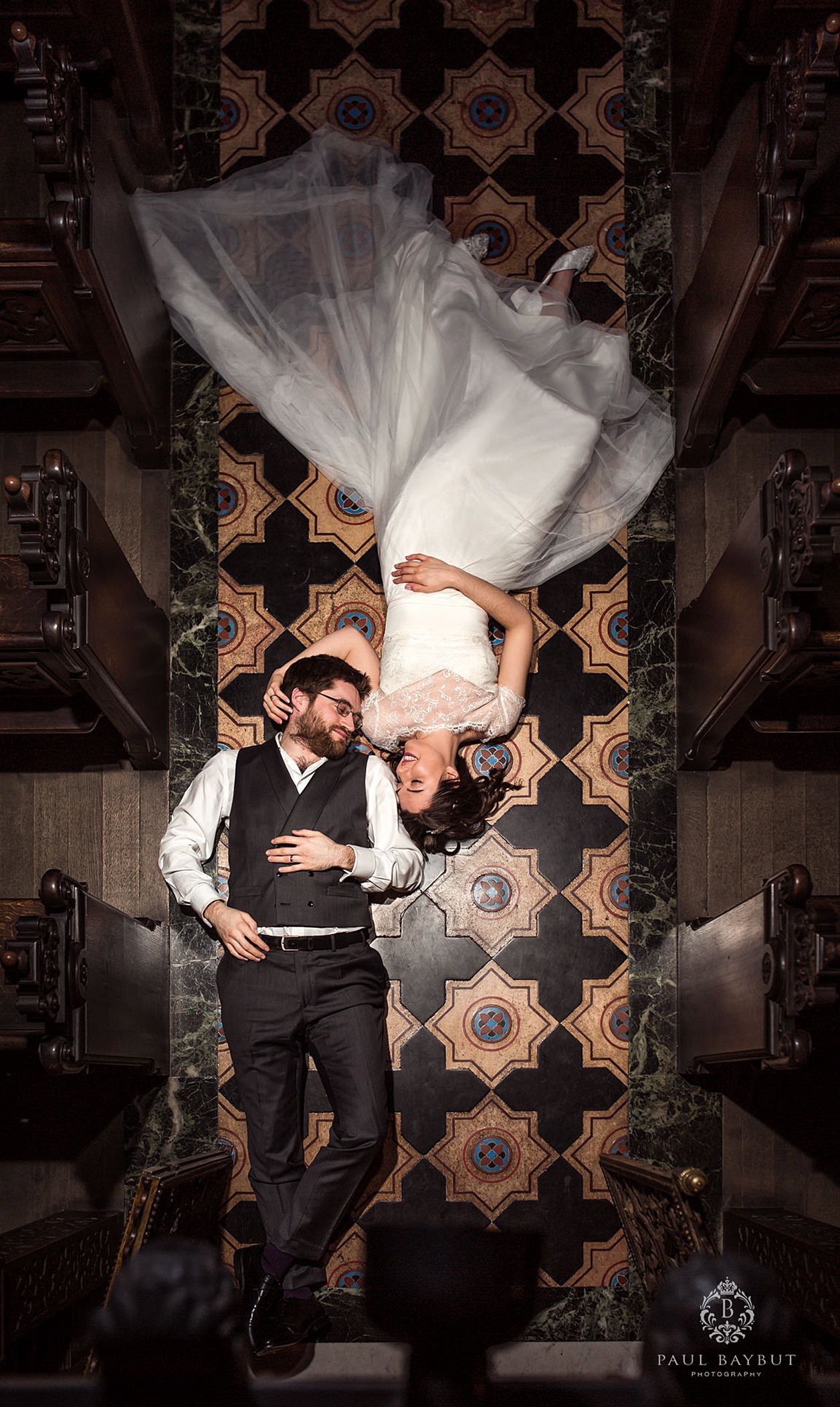 Creative upside-down wedding portrait shot on decorative patterned floor.