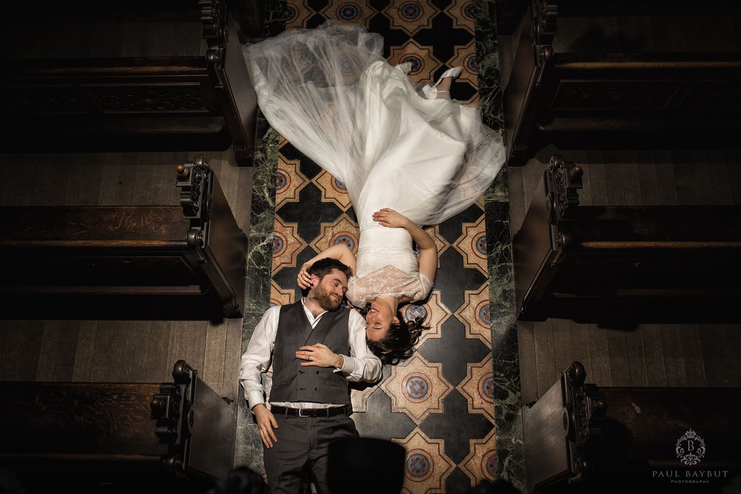 Creative overhead shot of couple on decorative floor with flowing white dress.