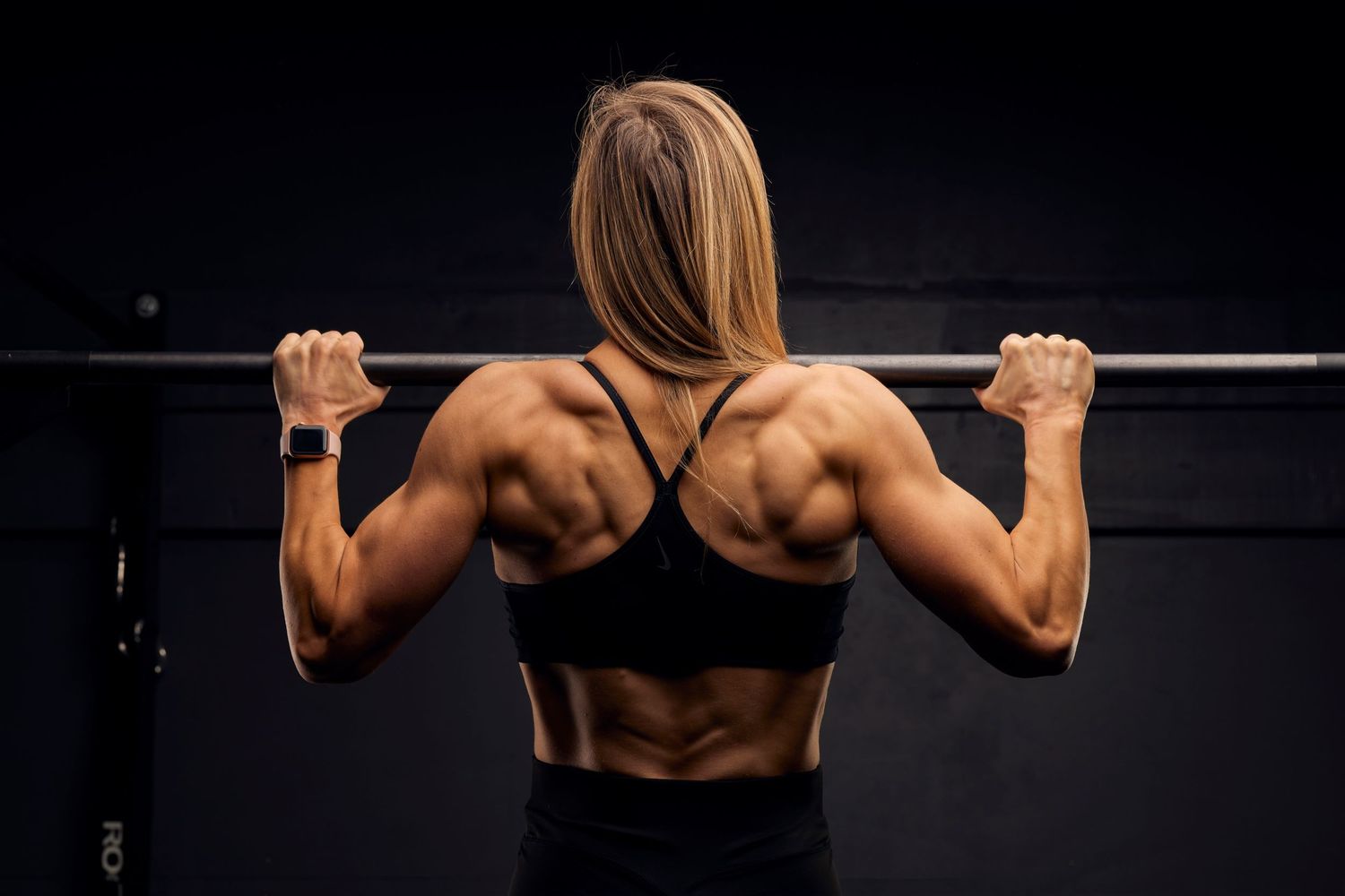 Strong and dramatic image of a female athlete doing a pull-up