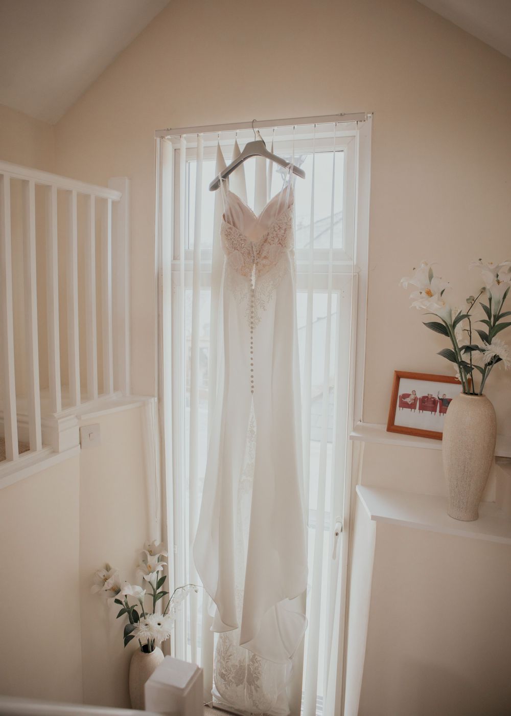 wedding dress hanging in window photography