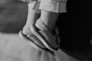 Close-up black and white shot of a child's foot wearing a casual sneaker.