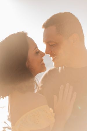 A romantic close-up portrait of a couple backlit by golden sunlight.