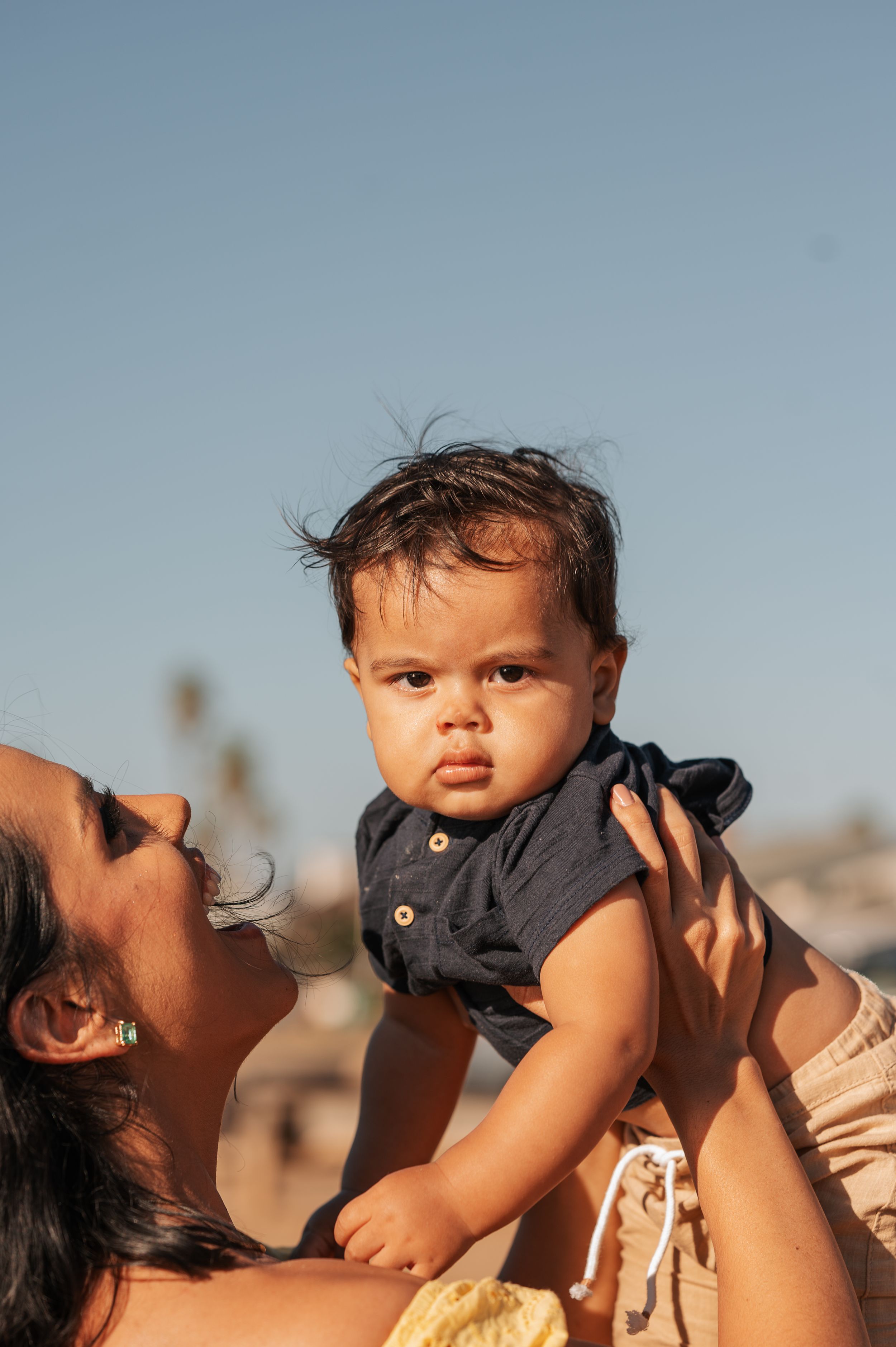 A joyful moment between a parent and baby against a blue sky background.