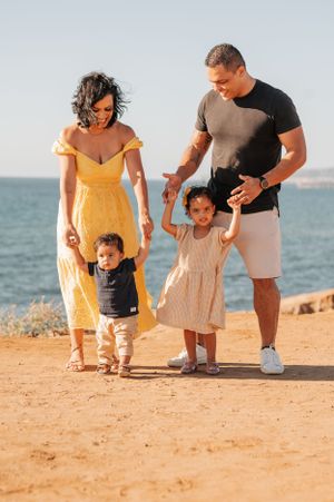 A family of four walking together on a coastal trail during golden hour.