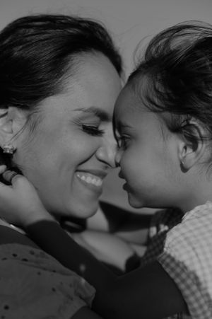 An intimate black and white portrait showing a tender moment between parent and child.