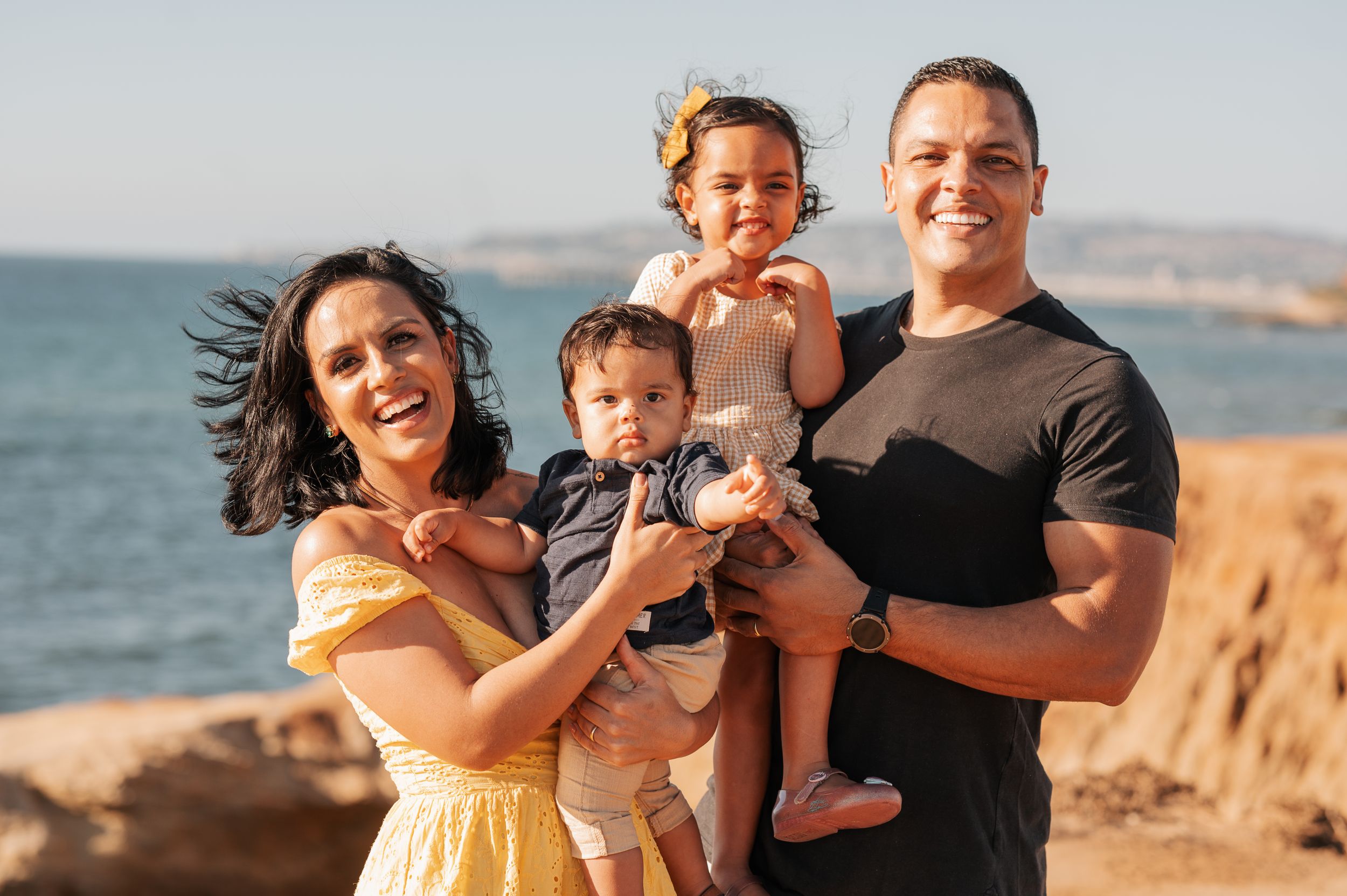 A happy family enjoying a sunny day at the beach with mountains in the background.