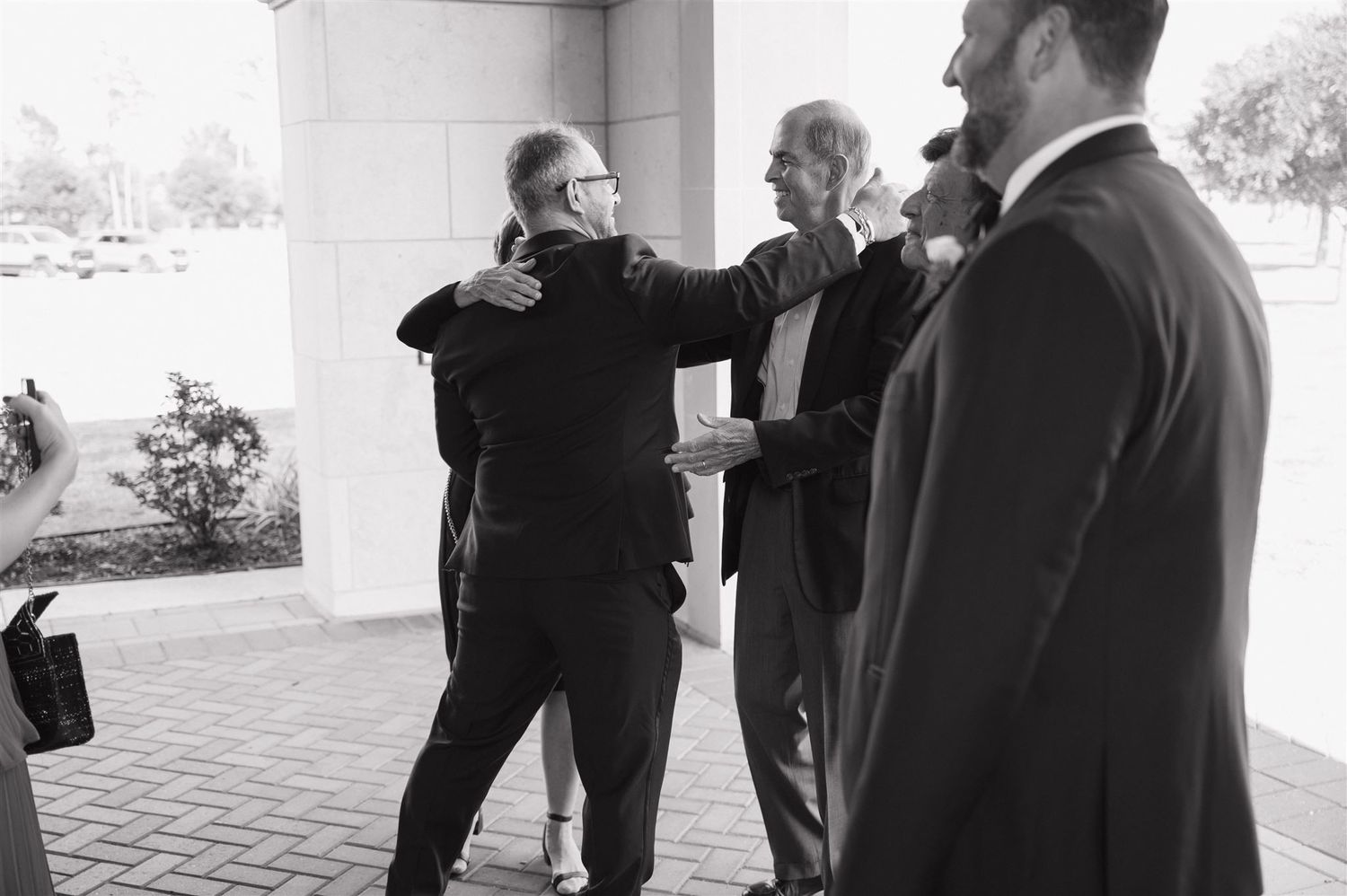 Black and white photo of wedding guests embracing during an emotional moment.