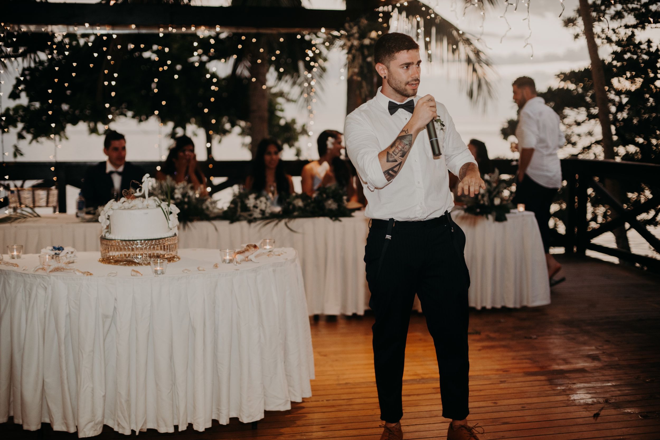 Wedding guest delivering a heartfelt speech during outdoor evening reception.
