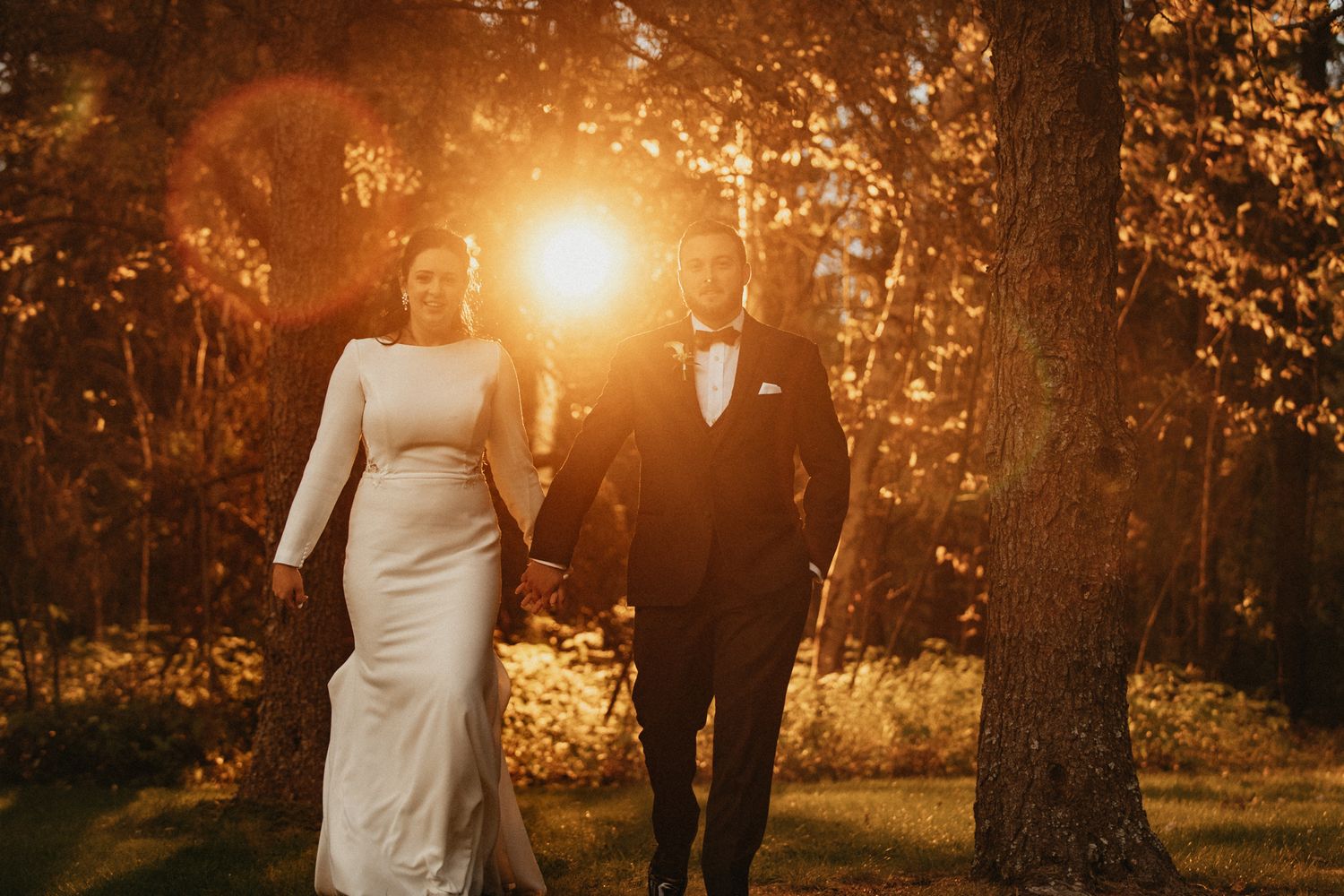 Golden hour wedding photography session in a wooded area with sunlight streaming through trees.