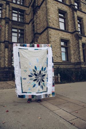 Memory quilt with a centre panel of a large starburst made from baby clothes with a sashing made from patchwork.