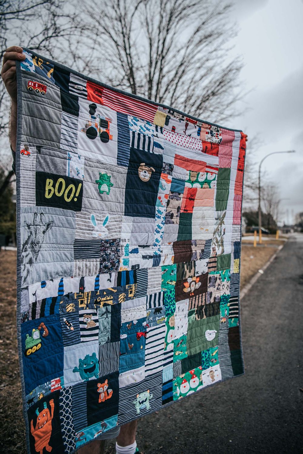 Patchwork memory quilt being held up in a road.