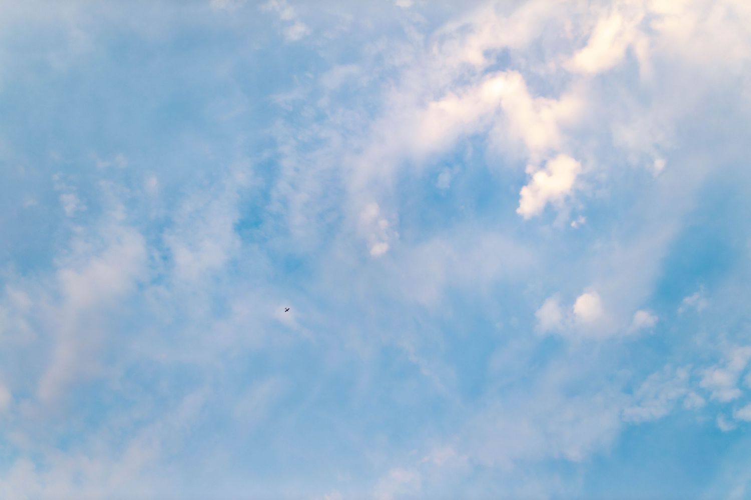 Bright blue sky with white puffy clouds in a panoramic view.
