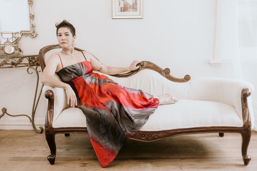 Elegant portrait of someone lounging on vintage furniture in a red and black dress.
