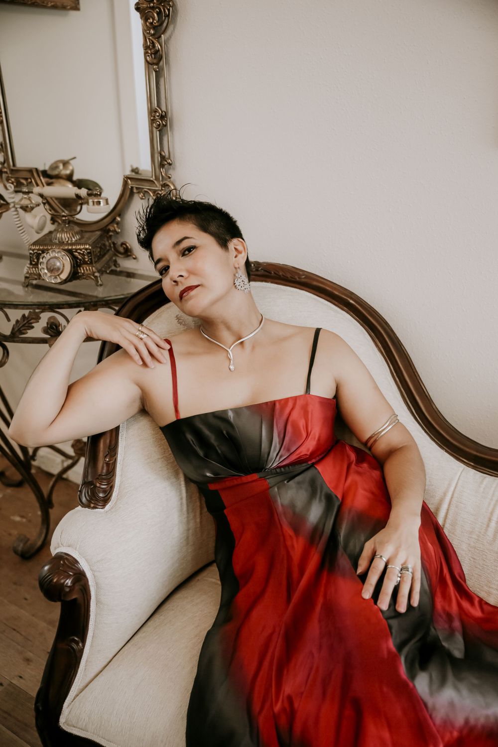 Glamour portrait on vintage furniture wearing red and black ombre dress.