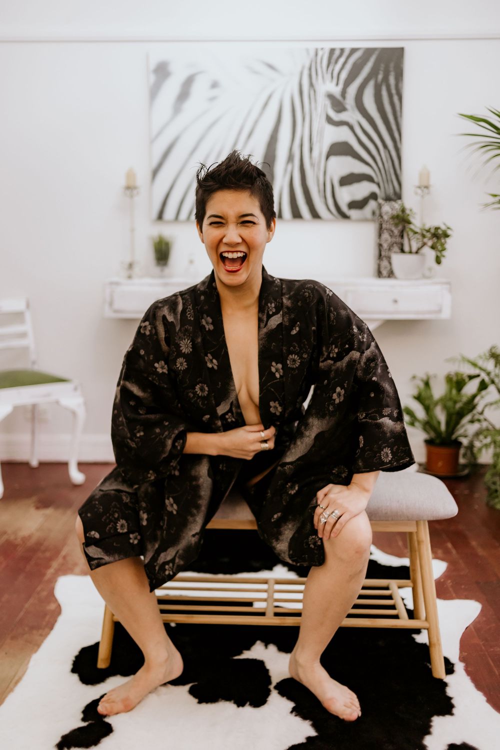 Person in black floral robe lounging on white bench with zebra artwork in background.