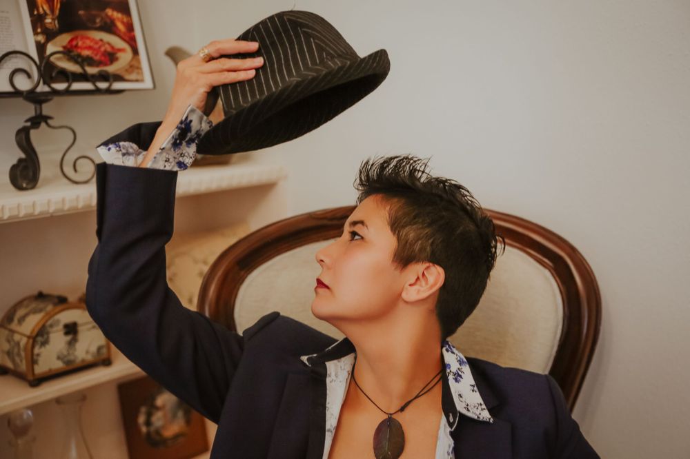 Artistic fashion portrait showing dramatic poses against neutral wall with framed artwork.