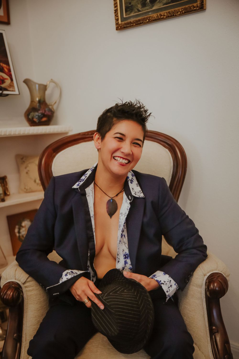 Person wearing navy blazer with lace trim seated in vintage armchair showing playful expressions.