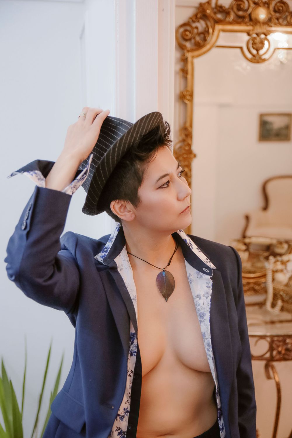 Fashion portrait in navy blazer with ornate gold mirror and decor in background.