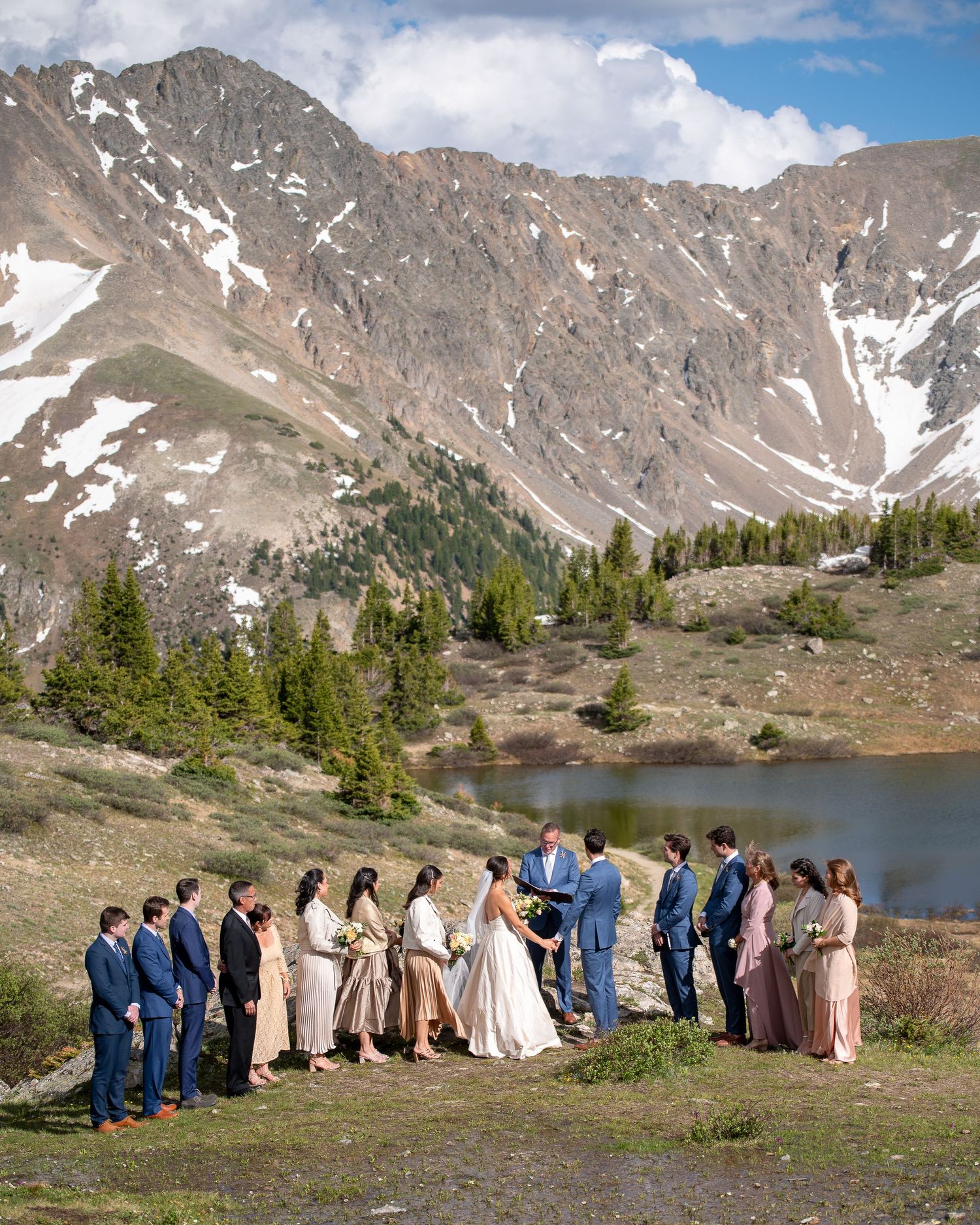 A mountain wedding ceremony overlooking an alpine lake with snow-capped peaks in the background.