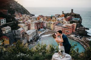 Bridal couple sharing a kiss with an epic coastal town view of Cinque Terre in Italy.