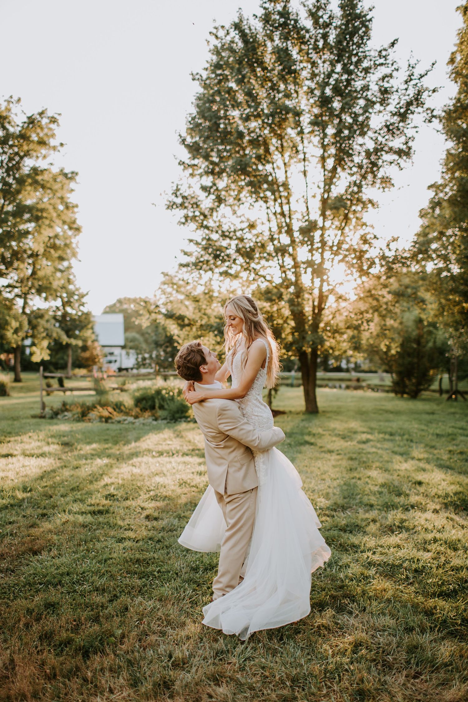 Couple embracing on grassy lawn during golden hour sunset.