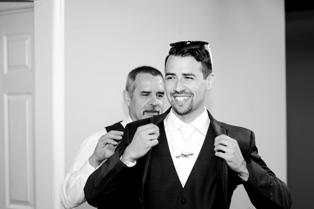 Two groomsmen in formal attire sharing a lighthearted moment while getting ready for a wedding.