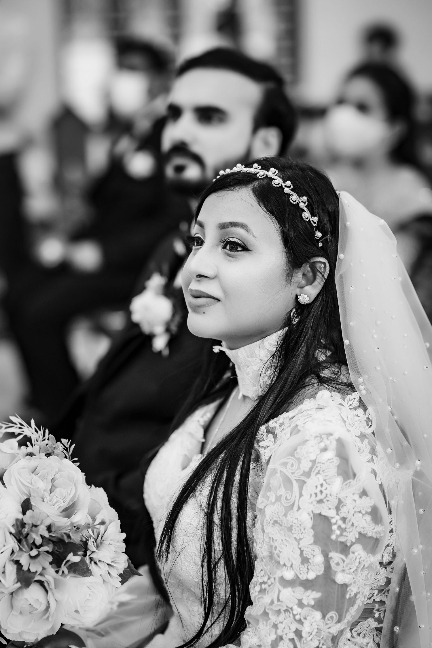 A black and white portrait of a bride wearing a delicate headpiece and lace dress.