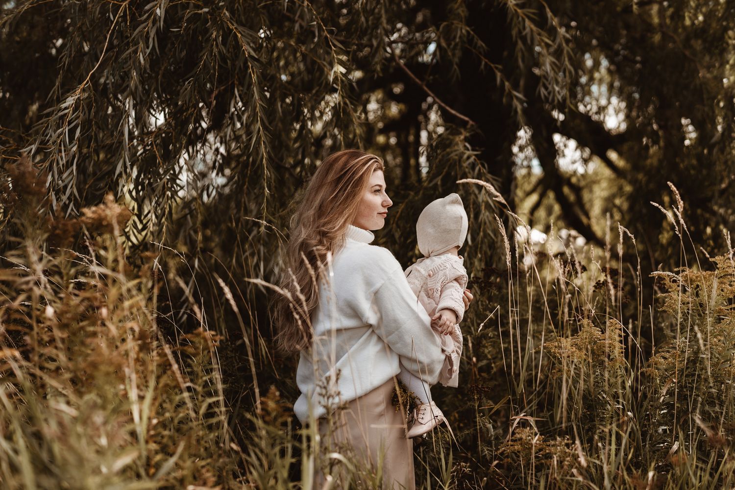 A sweet outdoor portrait of a family in white sweaters enjoying a natural wooded setting.