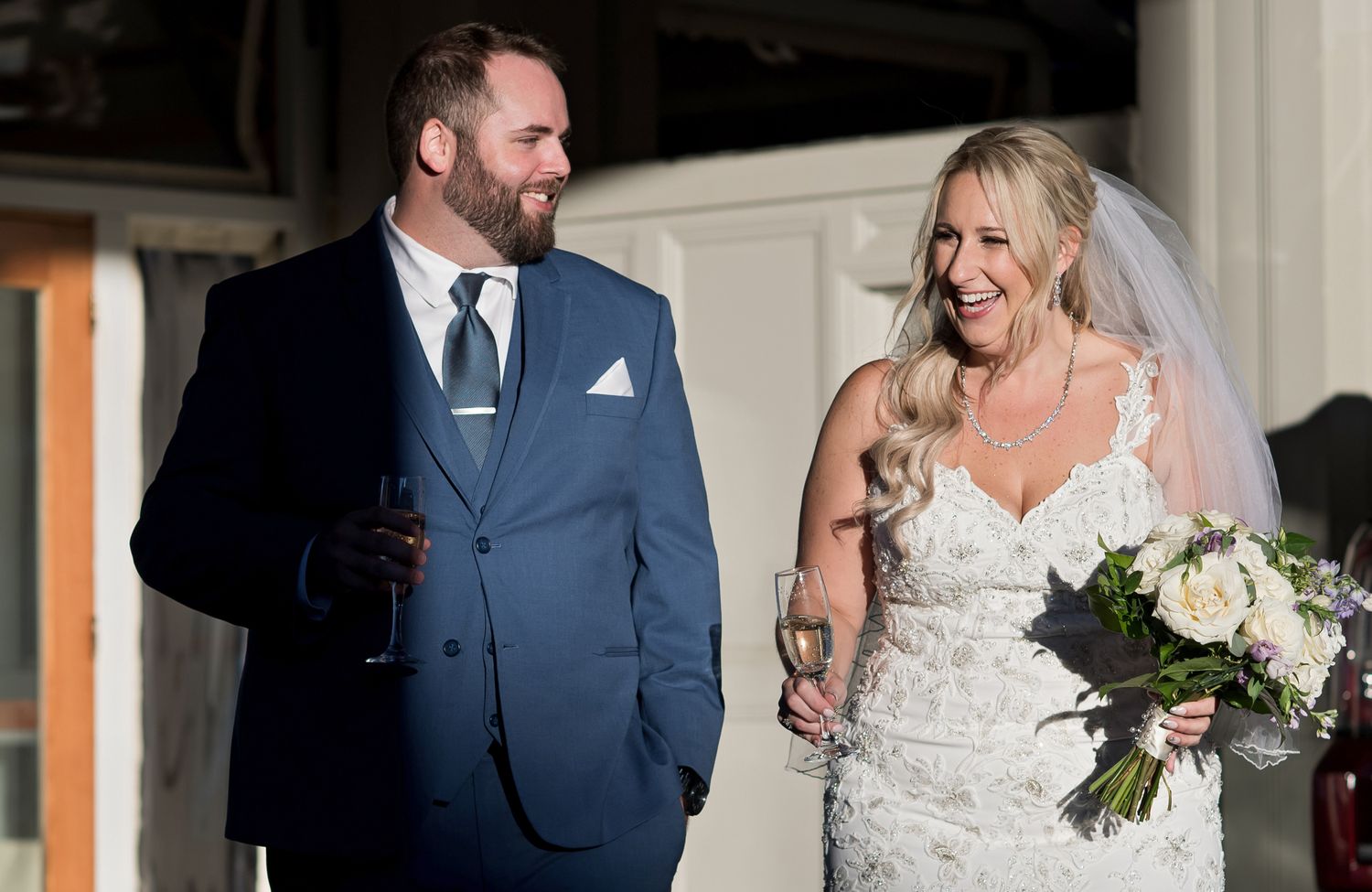 Wedding couple sharing candid moments outside a building with white columns.
