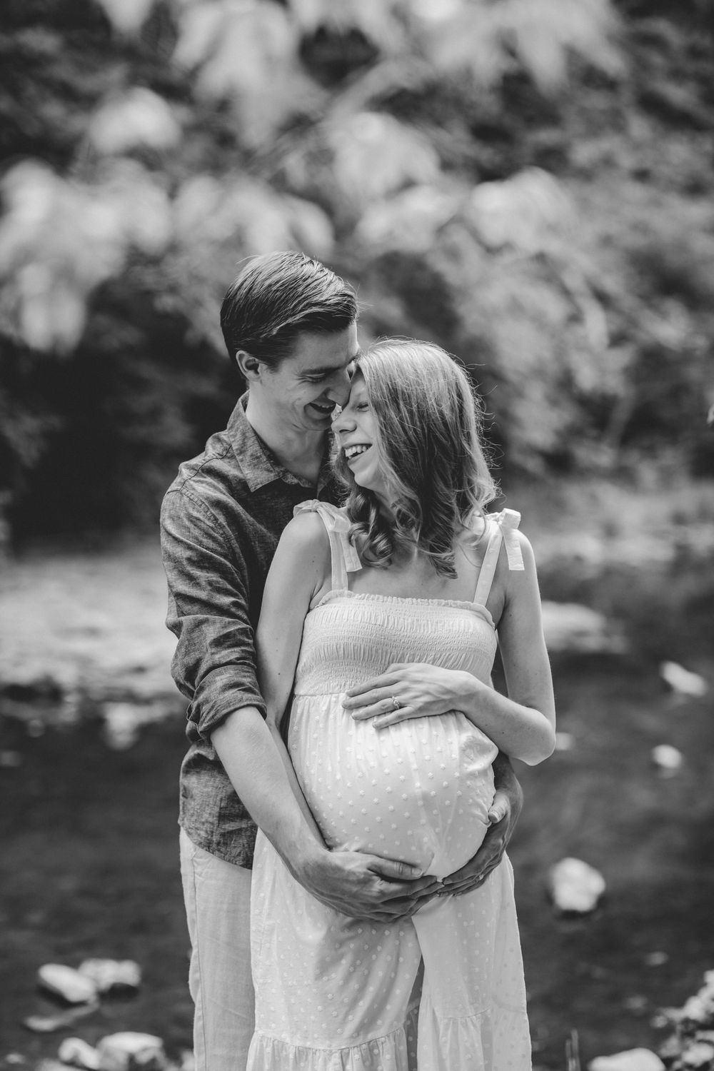Intimate black and white maternity photo in a natural outdoor setting.