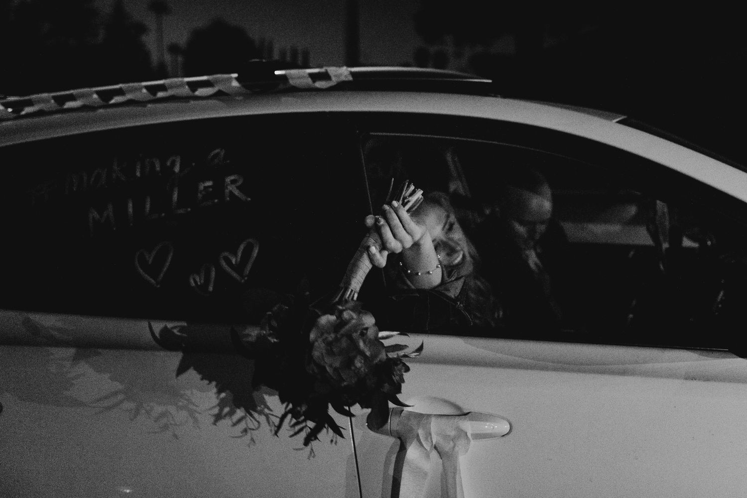 Black and white photo of a decorated wedding car at night.