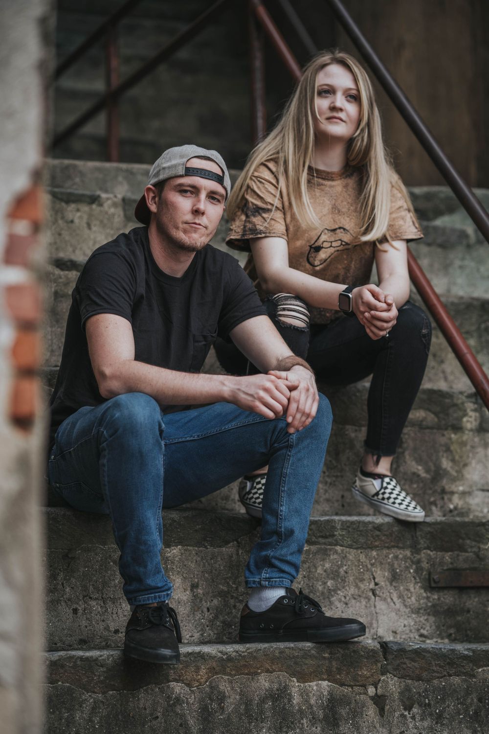 Casual couple portrait session on grungy urban staircase with industrial architectural details.