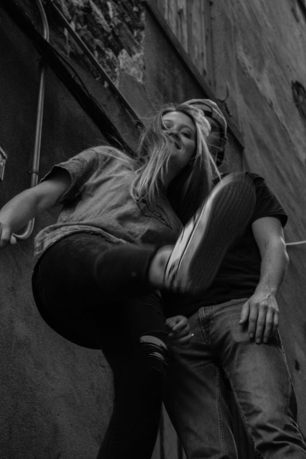Artistic black and white capture showing dramatic pose against textured urban wall.