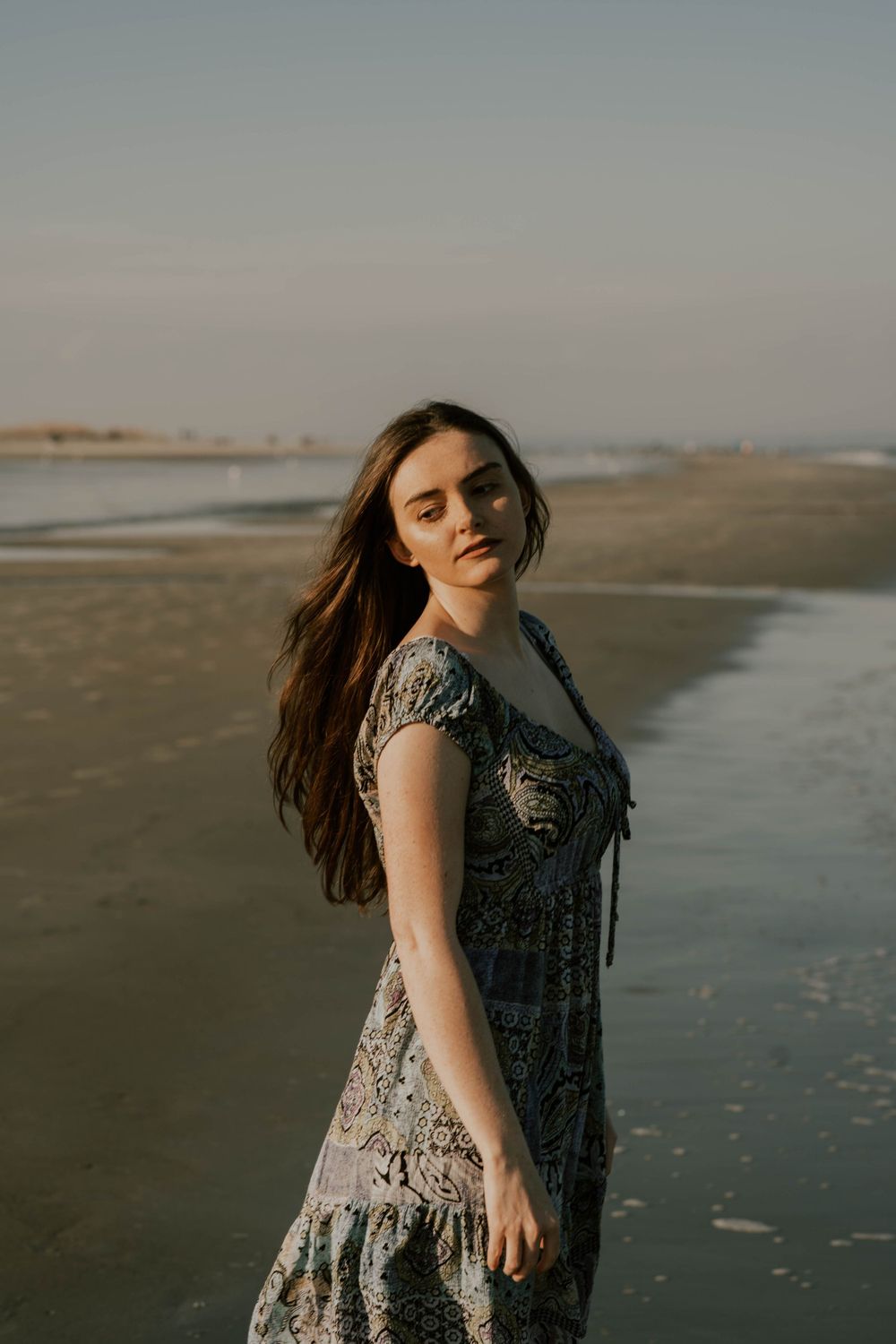 A windswept moment captured on the beach during golden hour with waves in the background.