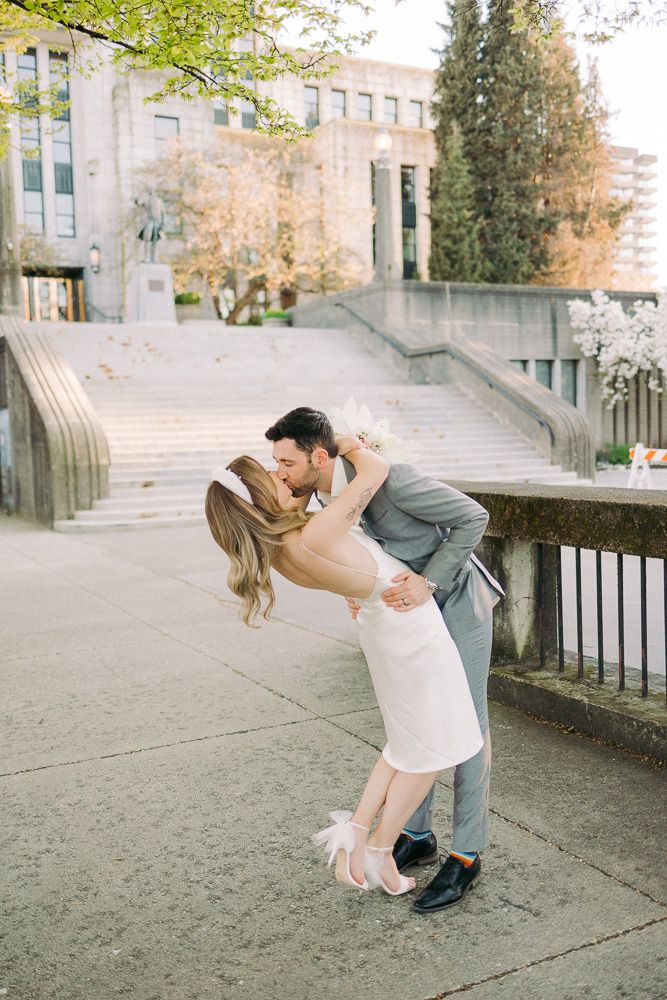 Romantic dip pose on concrete steps outside a stone building.
