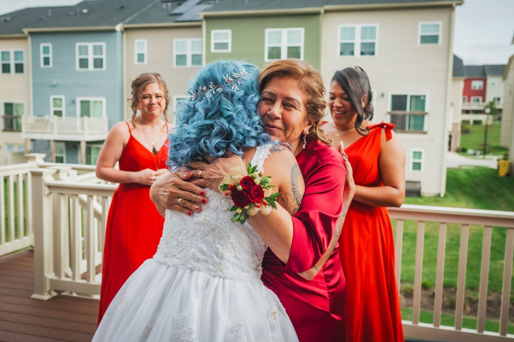 A wedding party shares a joyful moment on a deck with suburban houses in background.