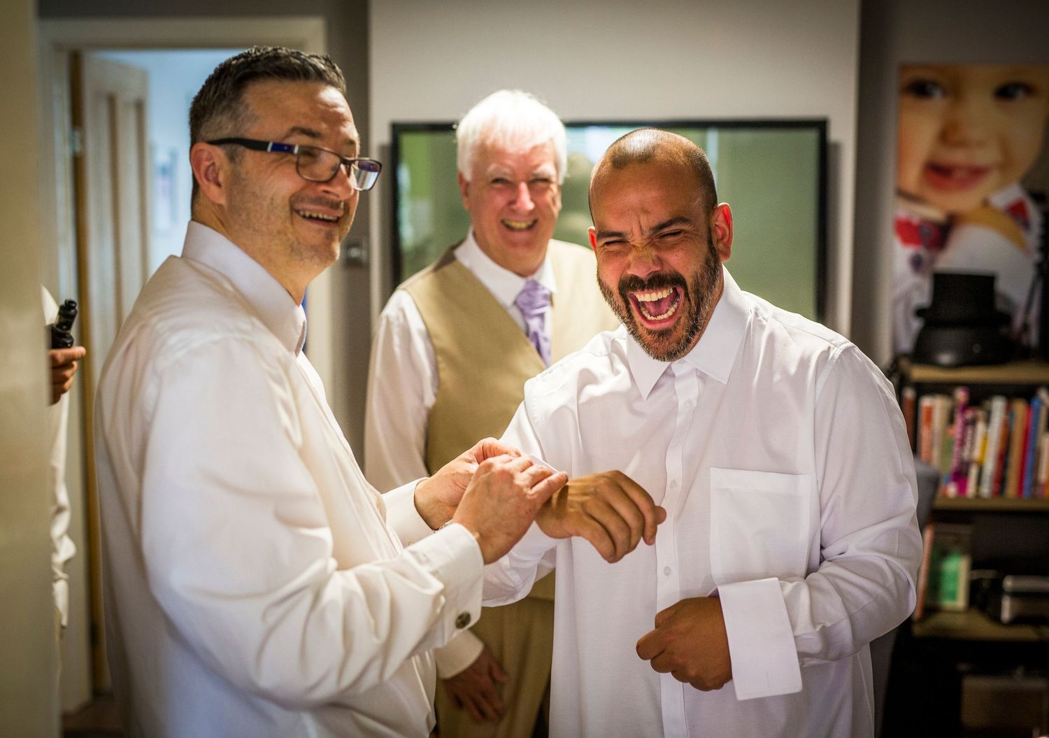 Wedding party members in white shirts share laughs and smiles during pre-ceremony preparations.