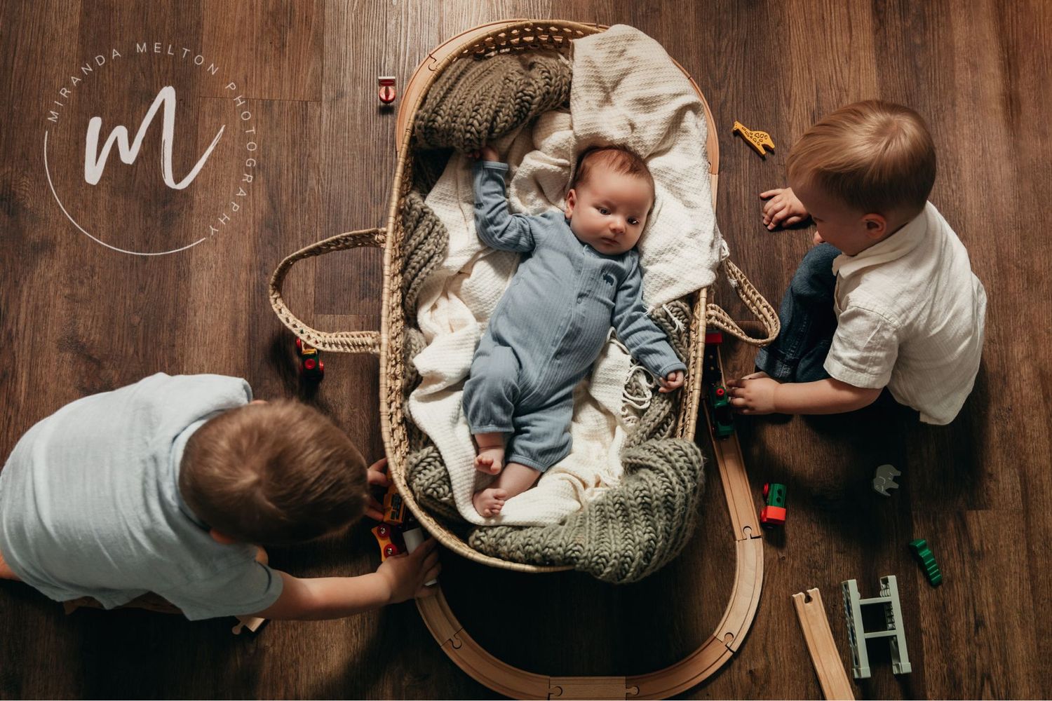 Overhead image of a newborn baby with his two older brothers in their family home. Concept for family photo ideas in the Twin Cities.