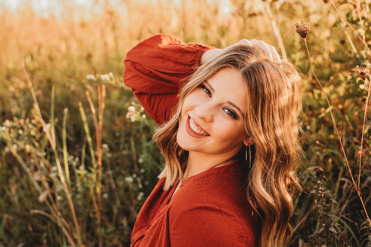 Portrait in golden field with person wearing rust-colored sweater during sunset.