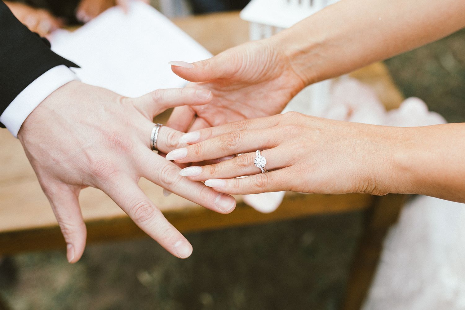 Close-up view of hands joined together in celebration with rings during wedding ceremony.