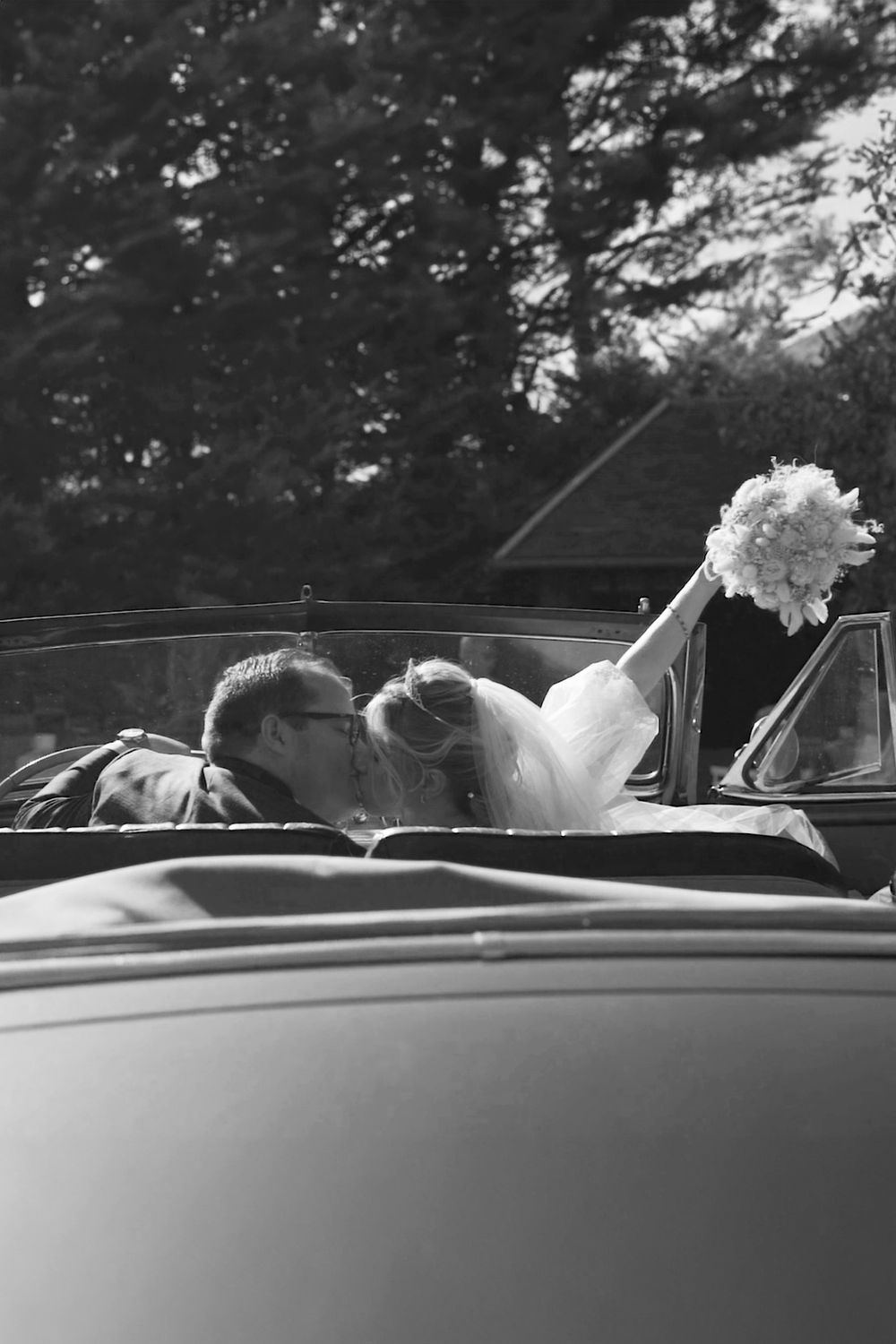 Black and white series showing couple in vintage car after their wedding ceremony.