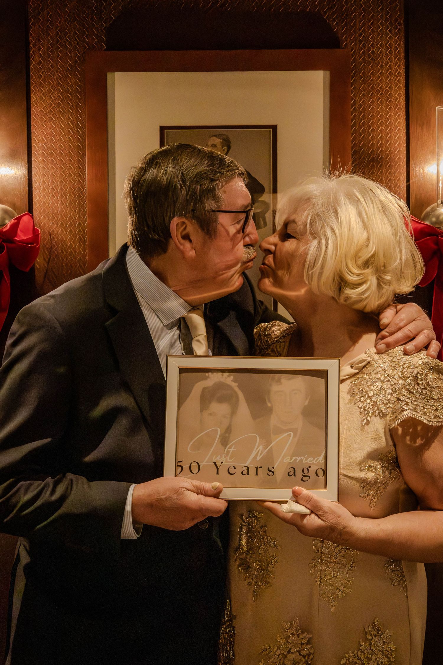Couple recreates wedding photo from 50 years ago while holding vintage photograph.