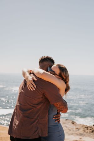 A heartfelt embrace shared between two people on a scenic coastal overlook.