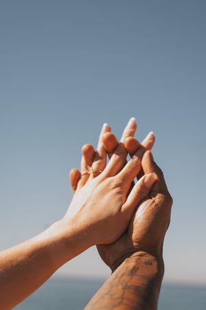Series of hands clasping together against a blue sky background.